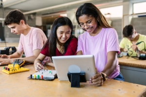 Group of diverse teenage students learning together at technology class